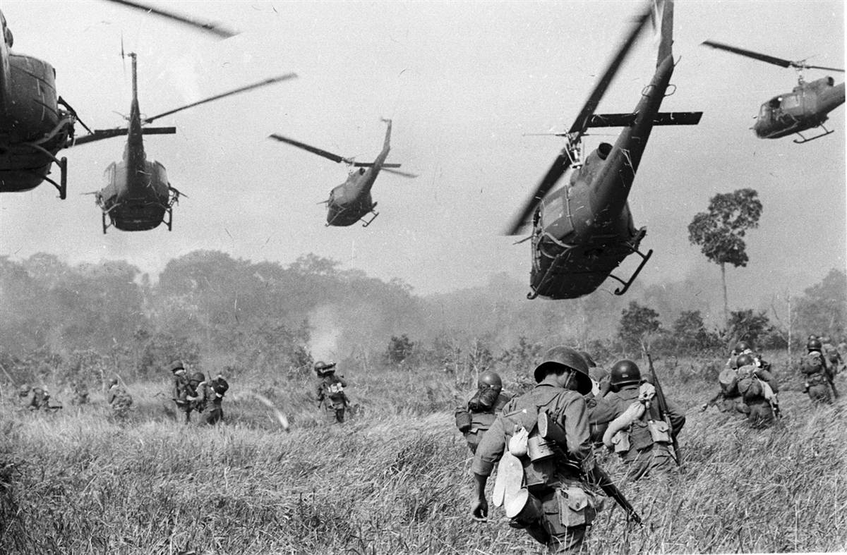 Bell UH-1 Iroquois helicopters fly over American solders in Vietnam